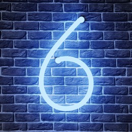 Image of Glowing neon number 6 sign on brick wall