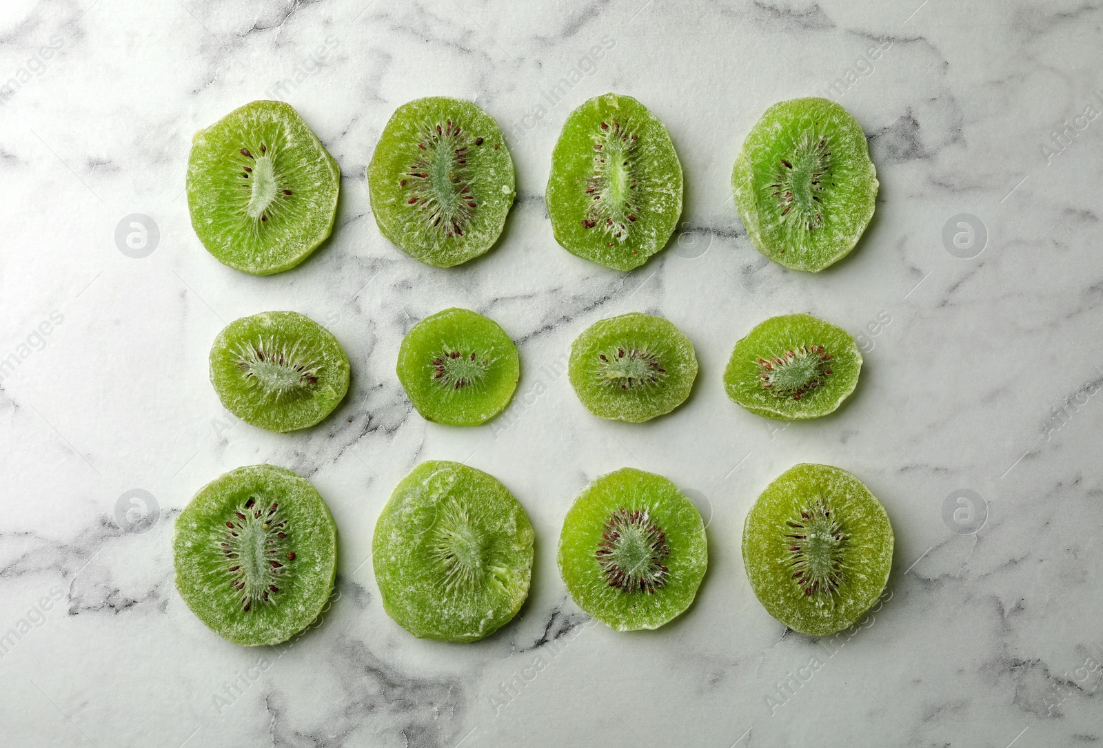 Photo of Slices of kiwi on marble background, flat lay. Dried fruit as healthy food