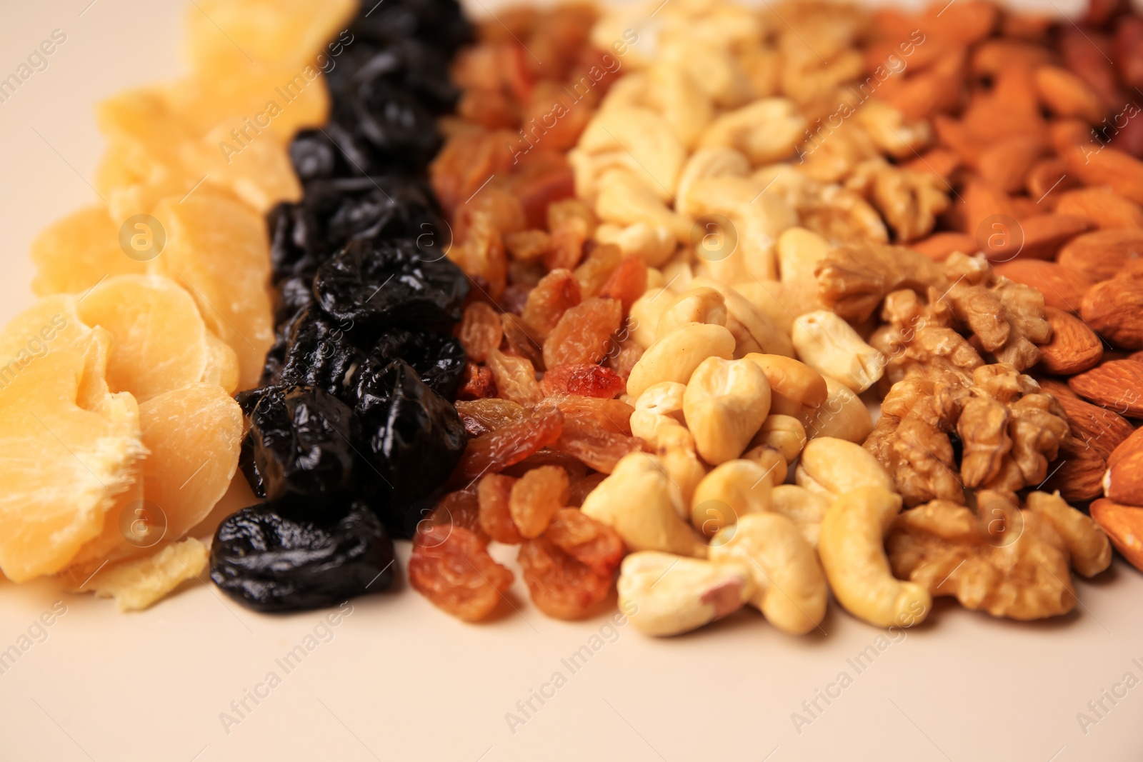 Photo of Mix of delicious dried nuts and fruits on beige background, closeup