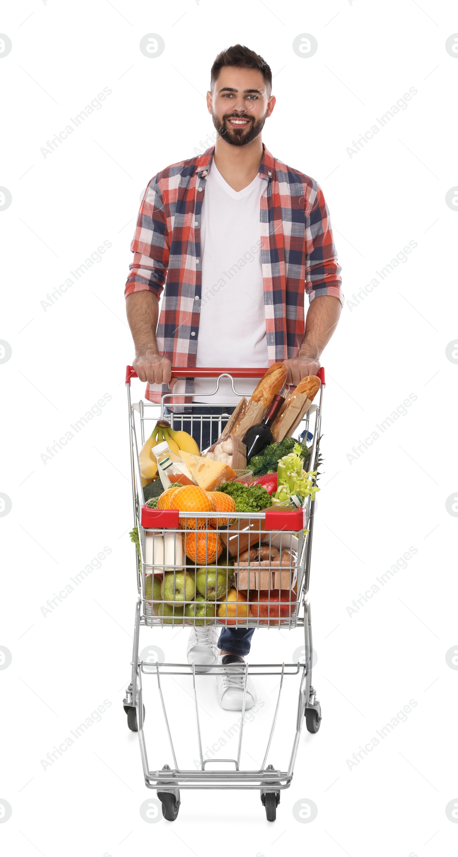 Photo of Happy man with shopping cart full of groceries on white background