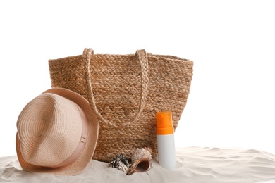 Stylish bag and beach accessories on sand against white background