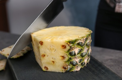 Cutting fresh pineapple on wooden board