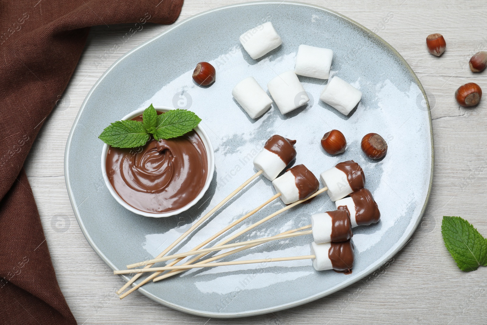 Photo of Tasty marshmallows dipped into chocolate on white wooden table, top view