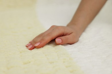 Photo of Woman touching soft yellow fabric, closeup view