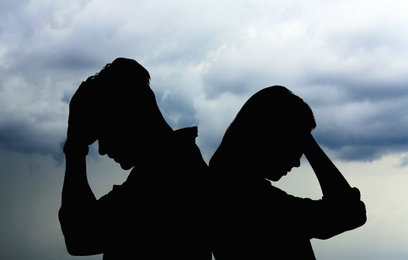 Image of Silhouettes of arguing couple against sky with heavy rainy clouds. Relationship problems