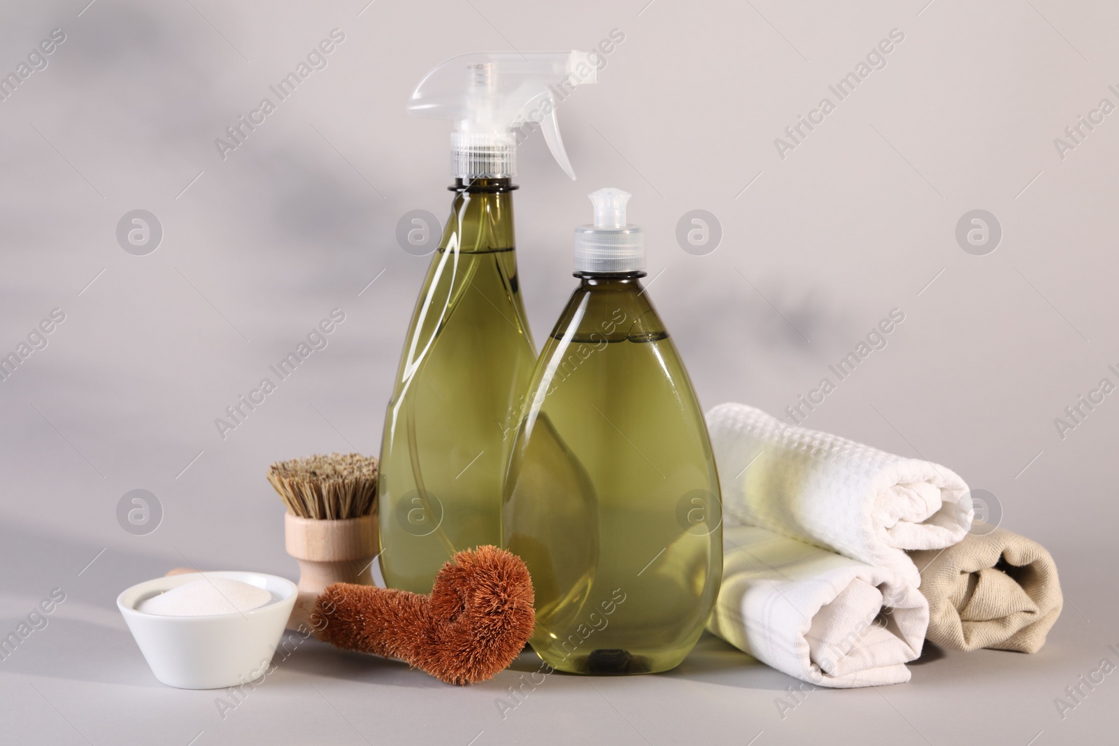 Photo of Bottles of cleaning product, brushes, rags and baking soda on light background