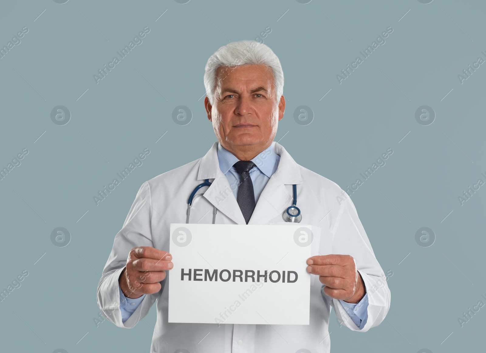 Photo of Doctor holding sign with word HEMORRHOID on light grey background