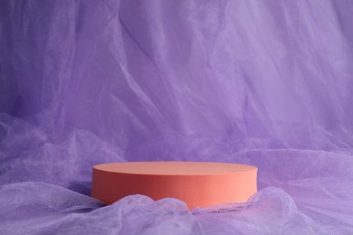 Photo of Round orange stand on violet tulle fabric, space for text. Stylish presentation for product