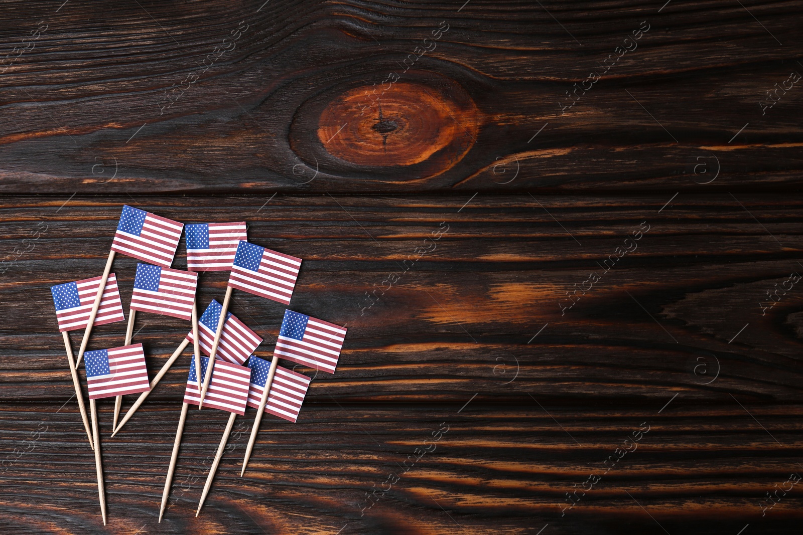 Photo of Small paper flags of USA on wooden table, flat lay. Space for text