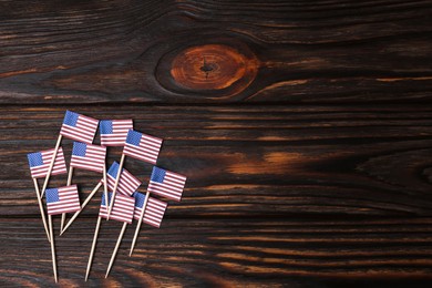 Small paper flags of USA on wooden table, flat lay. Space for text