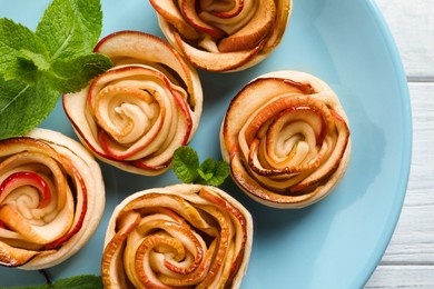 Photo of Freshly baked apple roses on white wooden table, top view. Beautiful dessert
