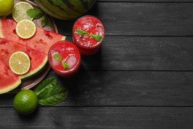 Photo of Glasses of delicious fresh watermelon juice, lime, mint and ice on black wooden table, flat lay. Space for text