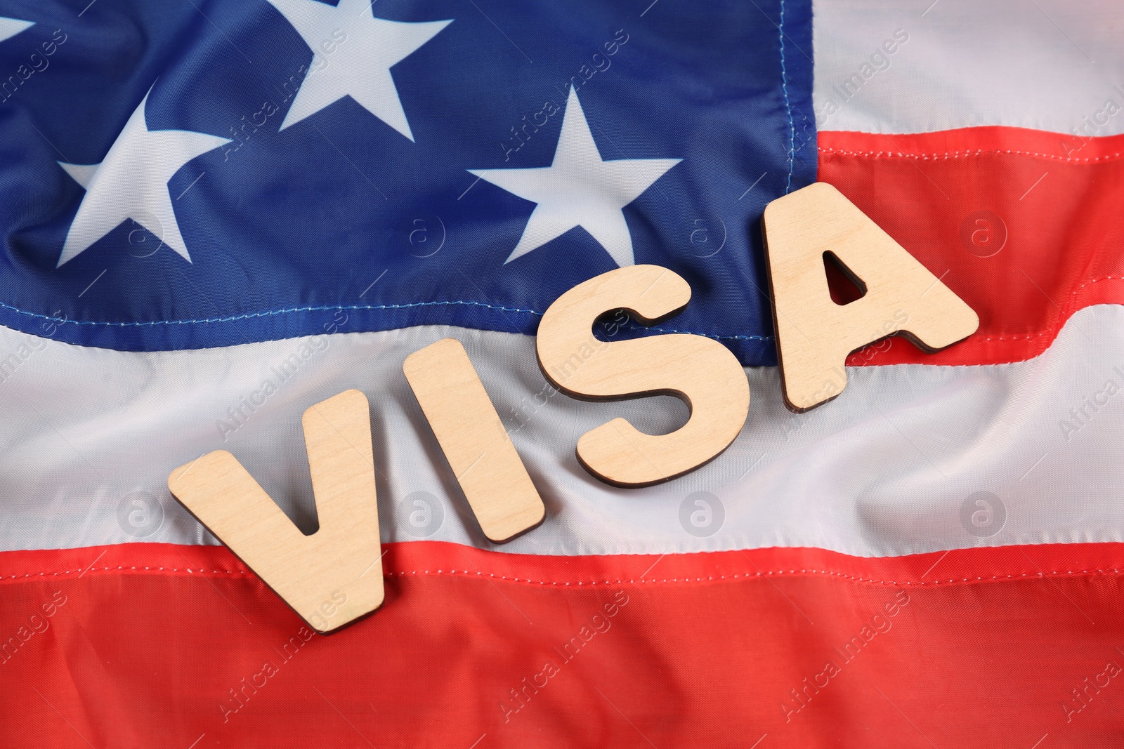 Photo of Word Visa made of wooden letters on American flag, flat lay. Immigration to USA