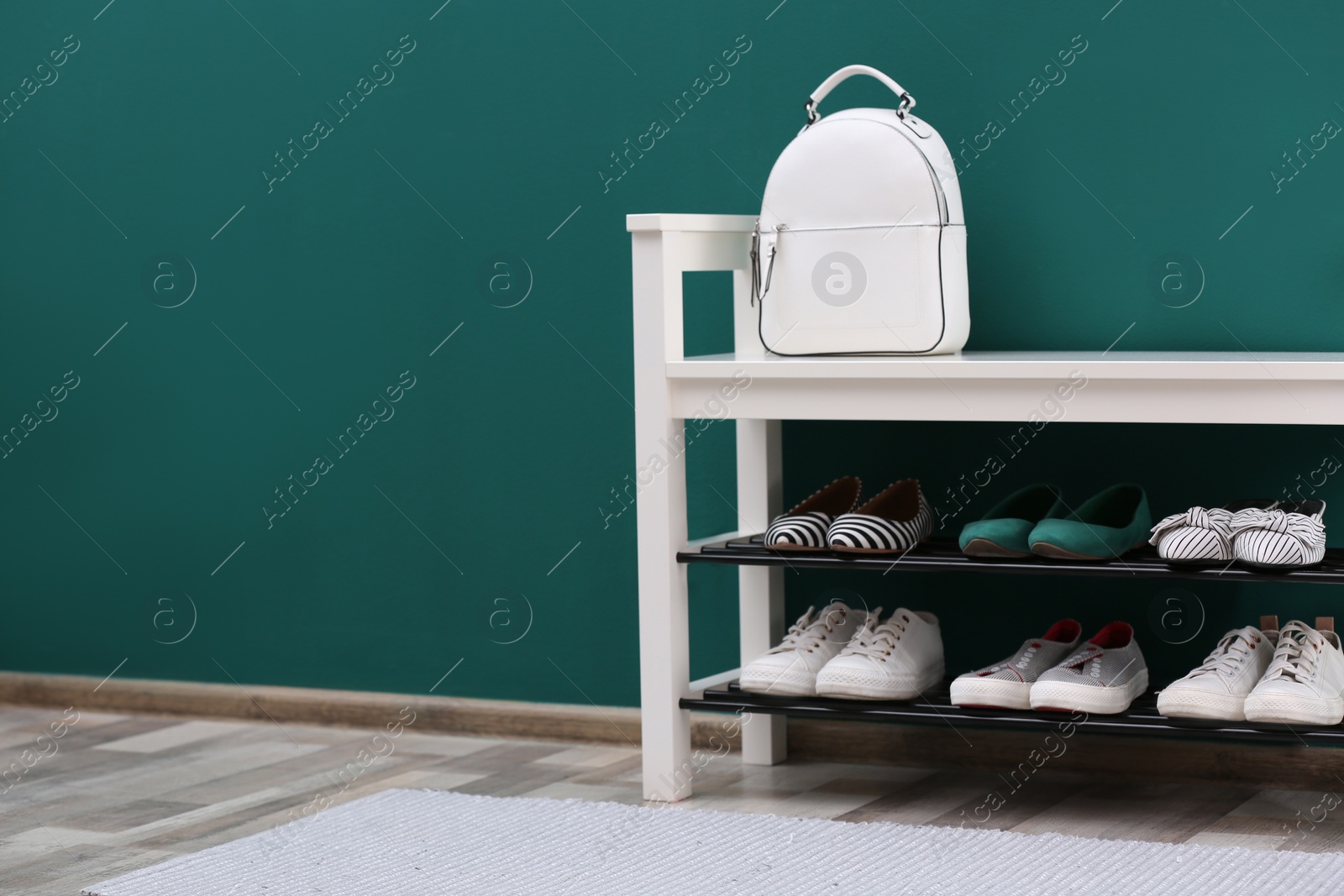 Photo of Shoe rack with different footwear near color wall, space for text. Stylish hallway interior