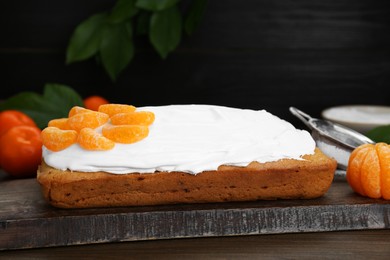 Delicious homemade yogurt cake with tangerines and cream on wooden table, closeup