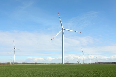 Photo of Modern wind turbines in field on sunny day. Alternative energy source