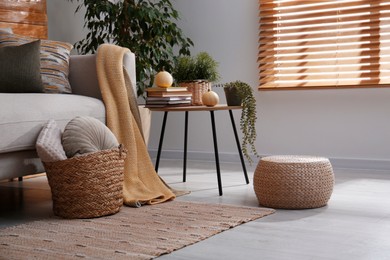 Stylish living room interior with comfortable sofa and wicker pouf