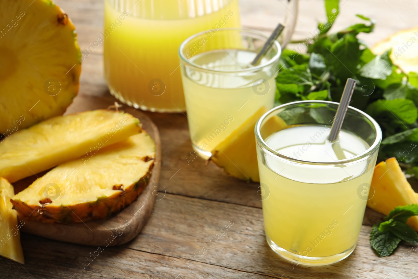 Photo of Delicious pineapple juice and fresh fruit on wooden table