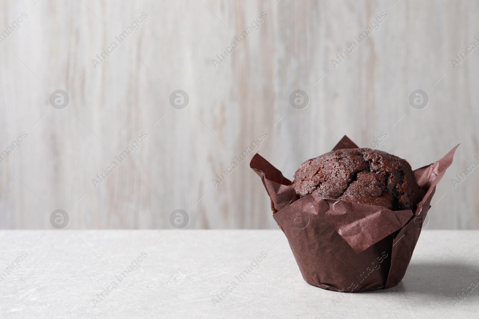 Photo of Tasty chocolate muffin on grey table, closeup. Space for text