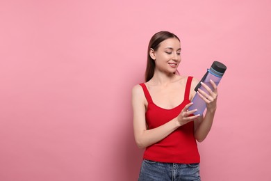 Beautiful young woman with transparent bottle on pink background, space for text