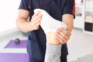 Photo of Physiotherapist working with young male patient in clinic