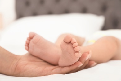 Mother holding her baby's feet on bed, closeup