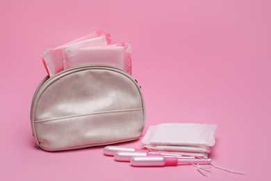 Bag, menstrual pads and tampons on pink background