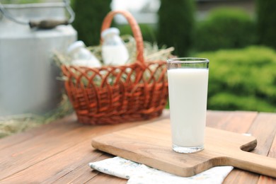 Photo of Tasty fresh milk in glass on wooden table outdoors. Space for text