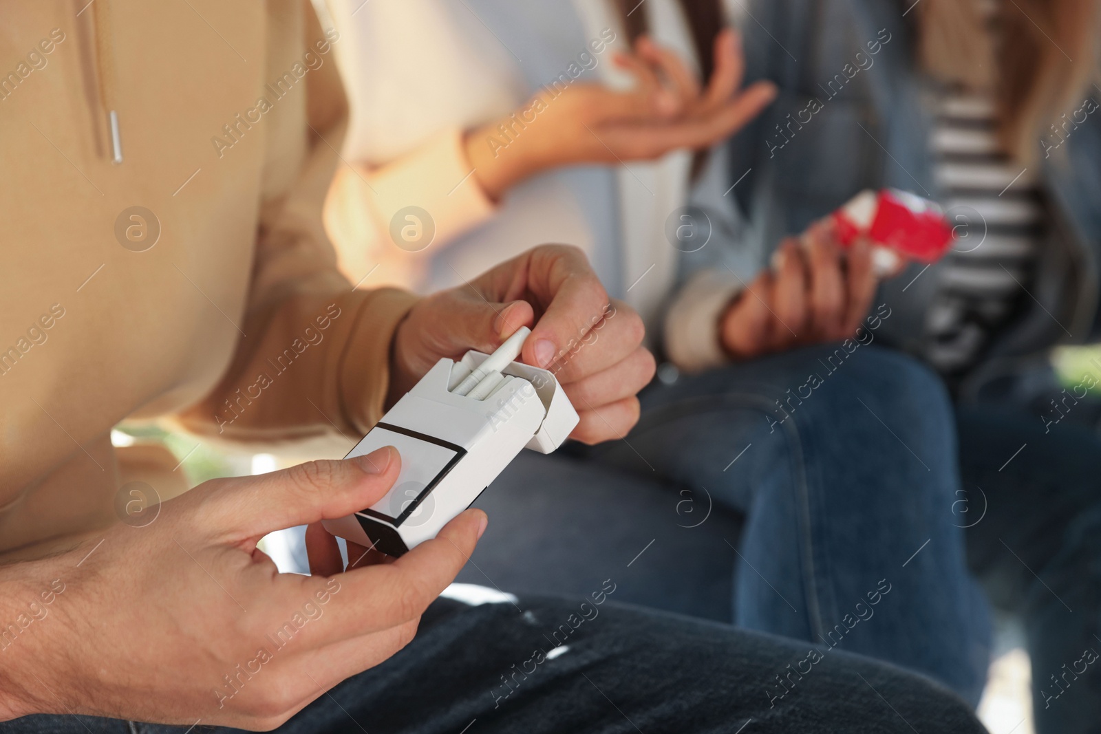 Photo of Man taking cigarette out of pack outdoors, closeup