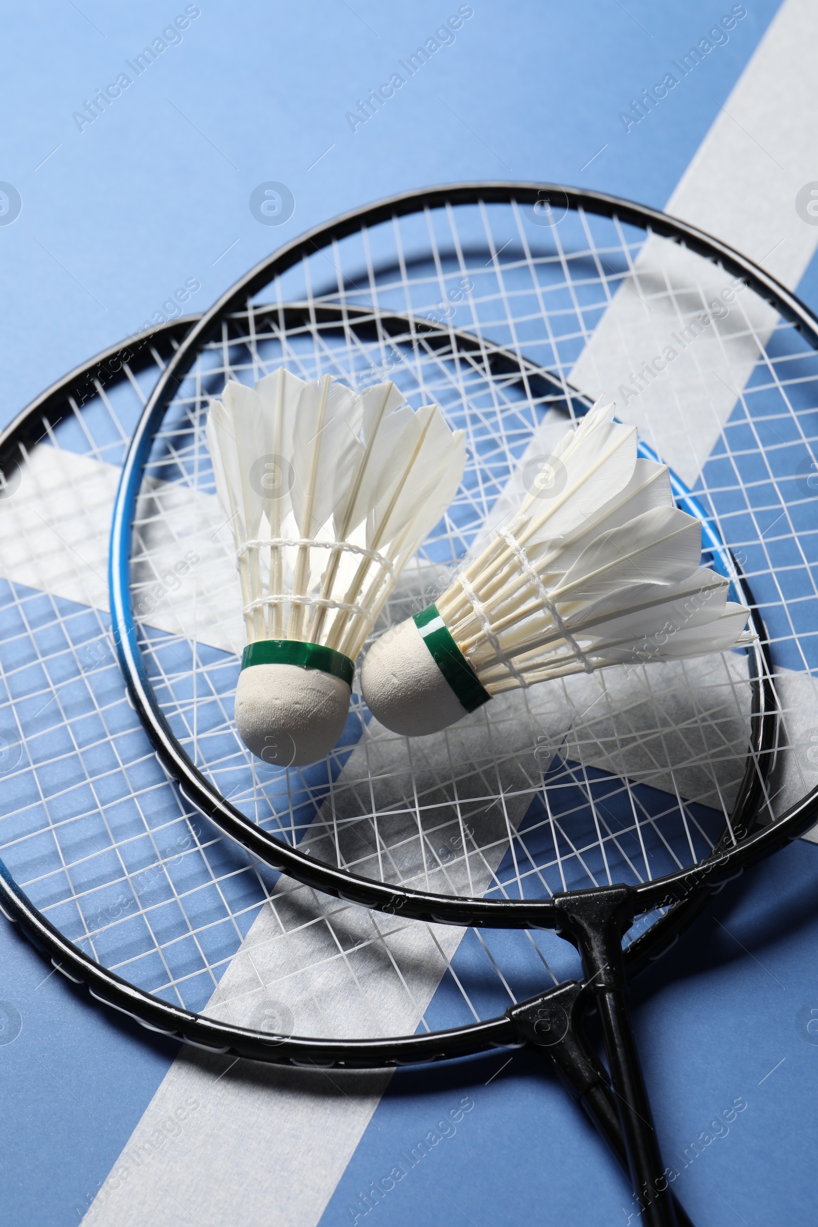 Photo of Feather badminton shuttlecocks and rackets on blue background, above view