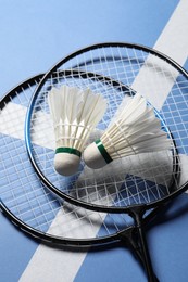 Photo of Feather badminton shuttlecocks and rackets on blue background, above view