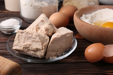 Compressed yeast, eggs, salt, dough and flour on wooden table