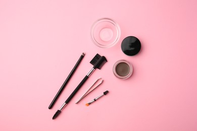 Photo of Eyebrow pomade with henna effect and professional tools on pink background, flat lay
