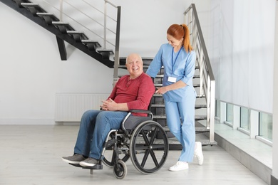 Photo of Nurse assisting senior man in wheelchair at hospital