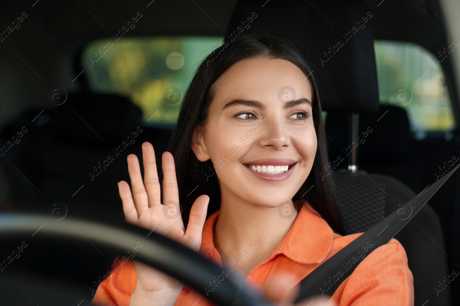 Photo of Enjoying trip. Happy young woman driving her car, view through windshield