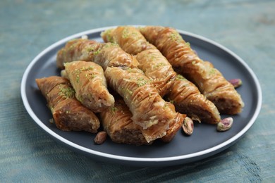 Photo of Delicious baklava with pistachio nuts on light blue wooden table, closeup