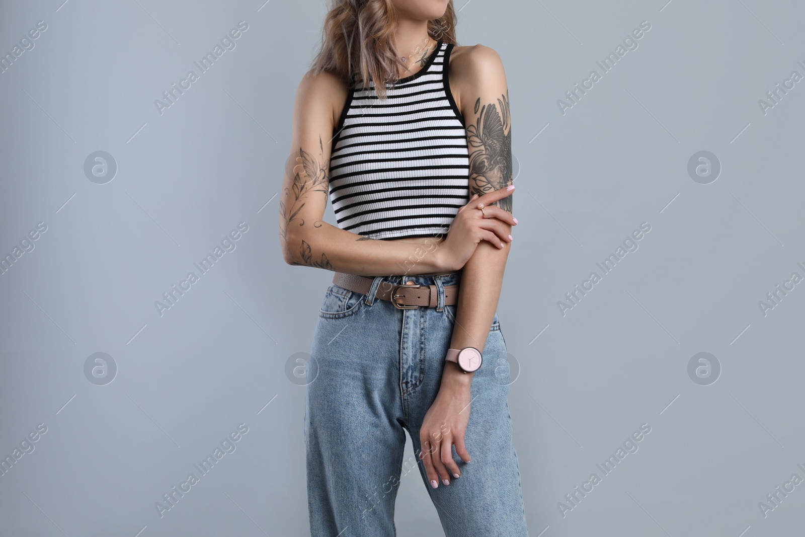 Photo of Beautiful woman with tattoos on body against grey background, closeup