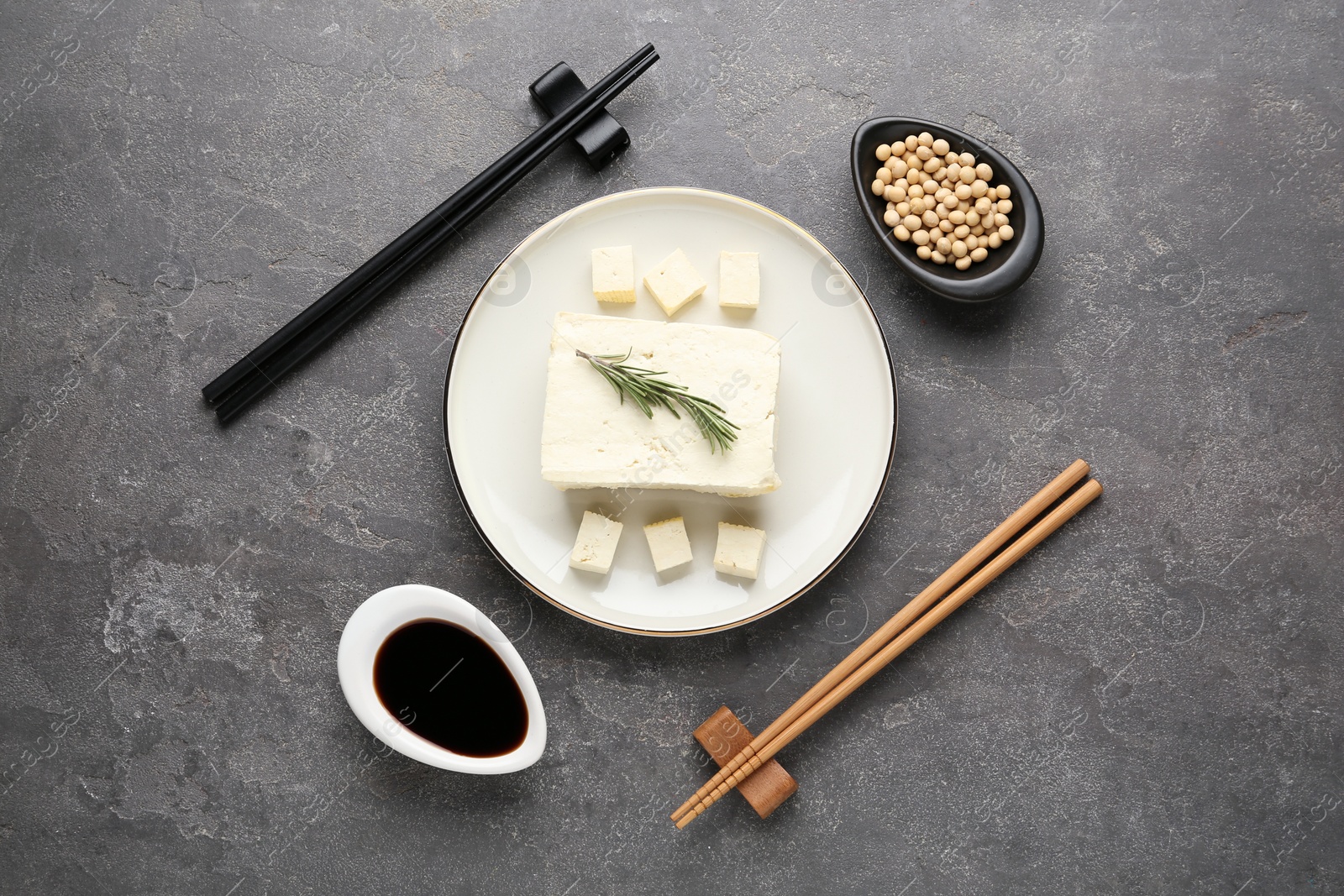 Photo of Cut tofu with soy sauce served on grey table, flat lay