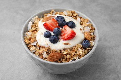 Photo of Tasty granola, yogurt and fresh berries in bowl on light grey table, closeup. Healthy breakfast
