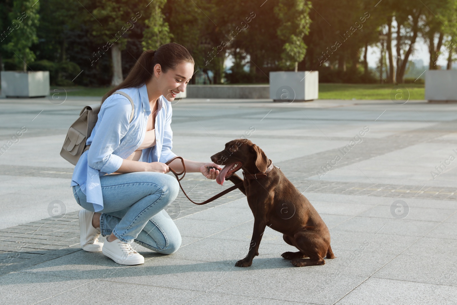 Photo of Young woman with her German Shorthaired Pointer dog on city street