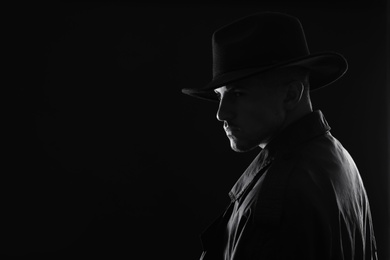 Photo of Old fashioned detective in hat on dark background, black and white effect. Space for text