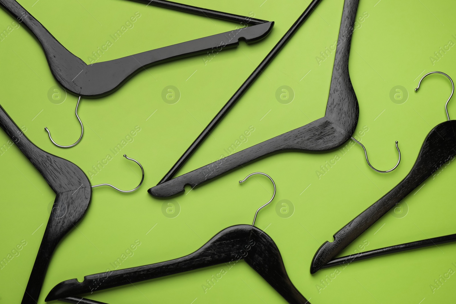 Photo of Empty clothes hangers on green background, flat lay