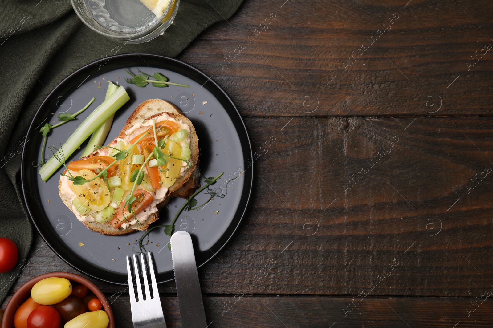 Photo of Tasty vegan sandwich with tomatoes, celery and microgreens on wooden table, flat lay. Space for text