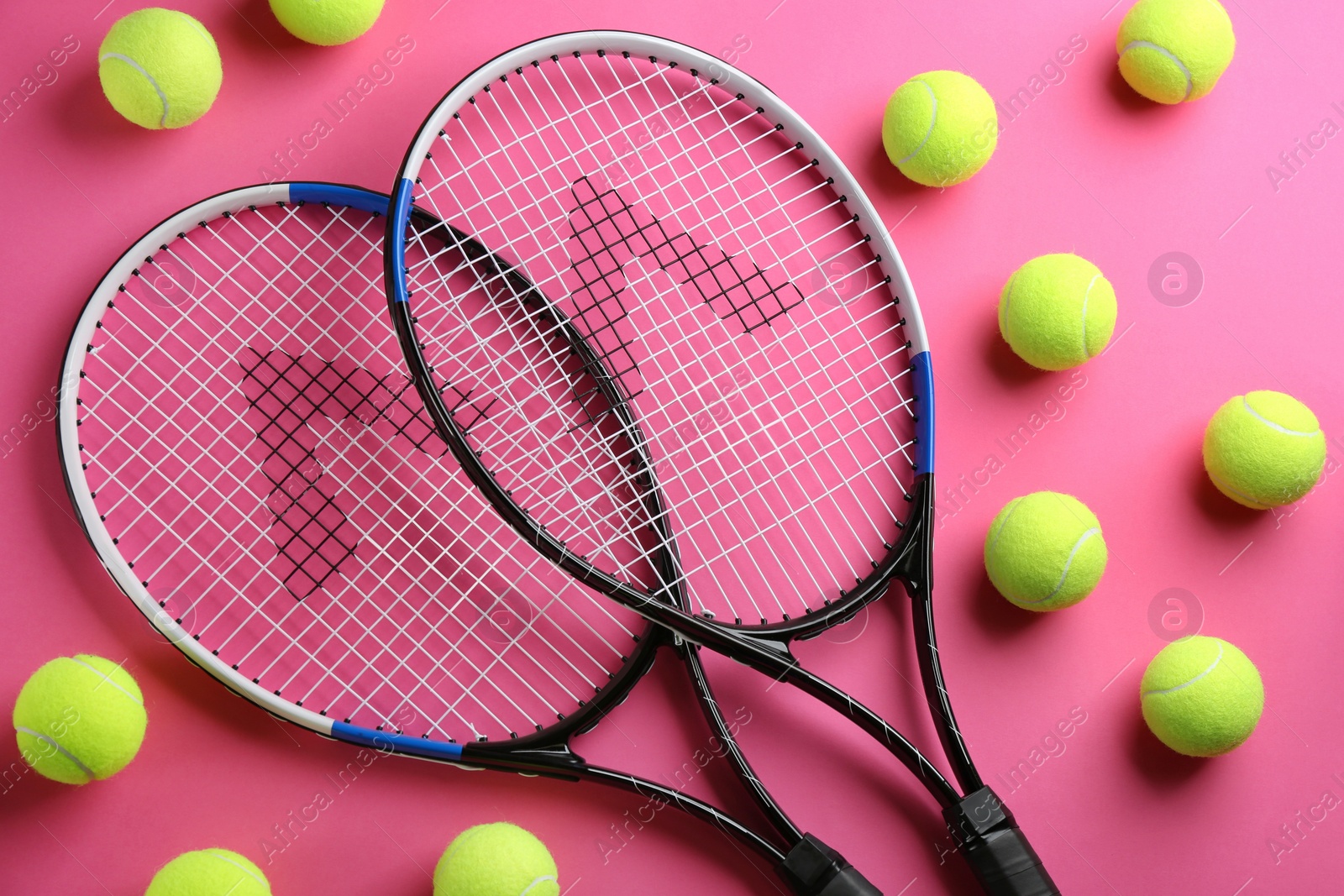 Photo of Tennis rackets and balls on pink background, flat lay. Sports equipment