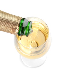 Pouring champagne from bottle into glass on white background. Festive drink