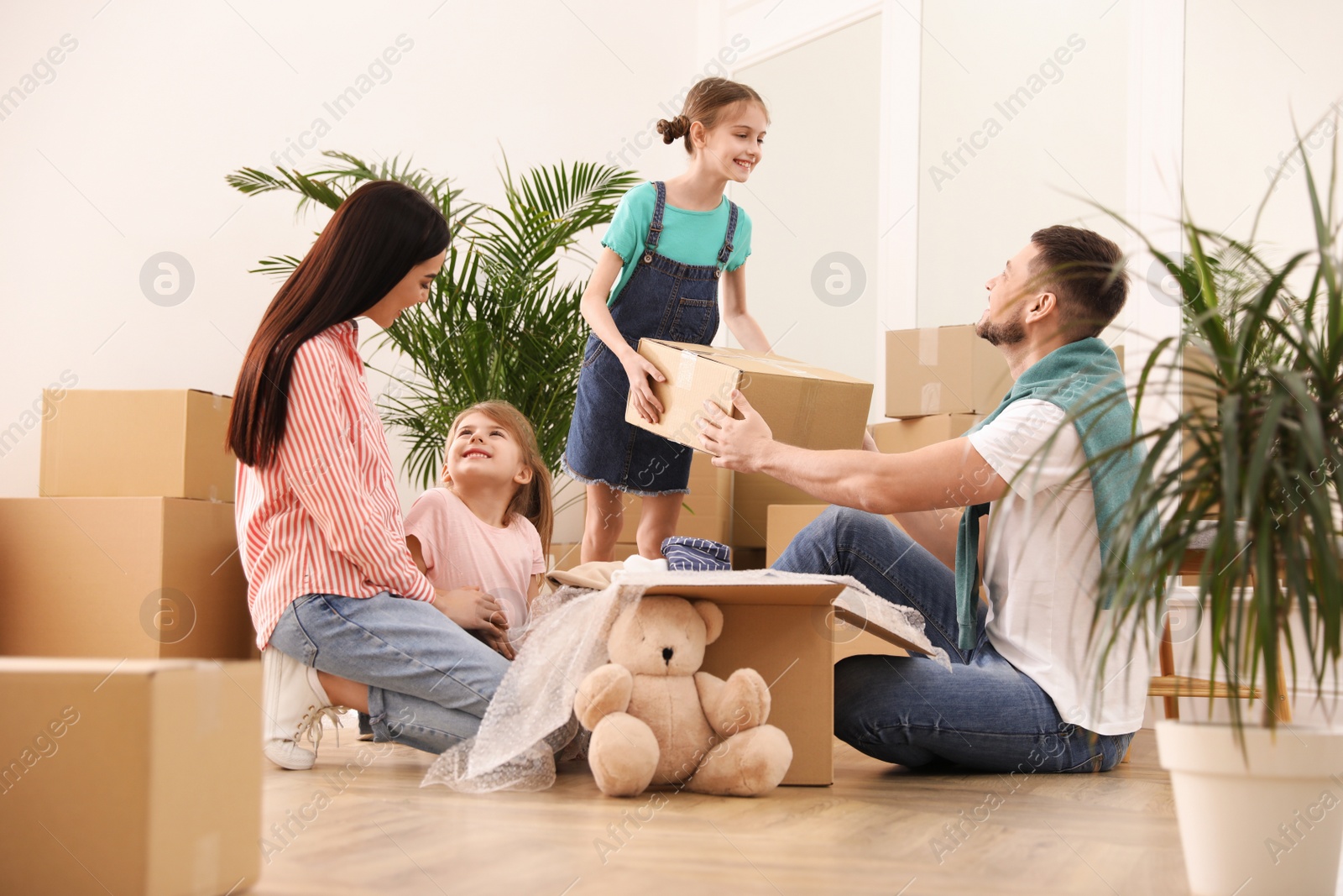 Photo of Happy family unpacking moving boxes in new house
