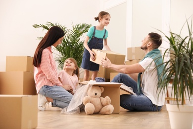 Happy family unpacking moving boxes in new house