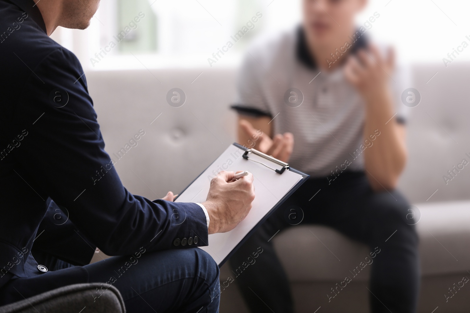 Photo of Psychotherapist working with young man in office, closeup