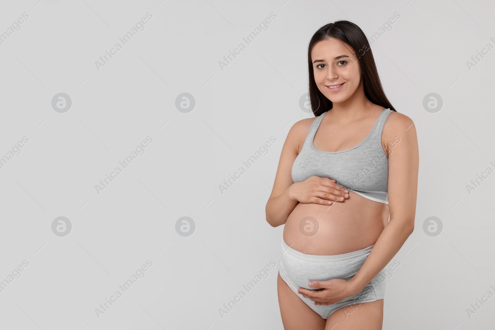 Photo of Beautiful pregnant woman in comfortable maternity underwear on grey background, space for text