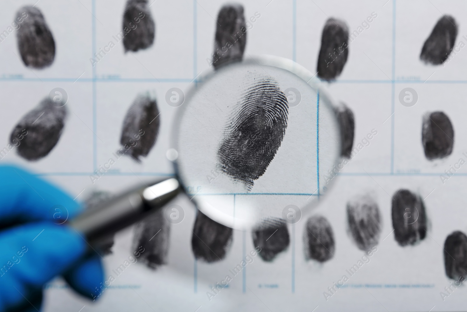 Photo of Criminalist exploring fingerprints with magnifying glass, closeup